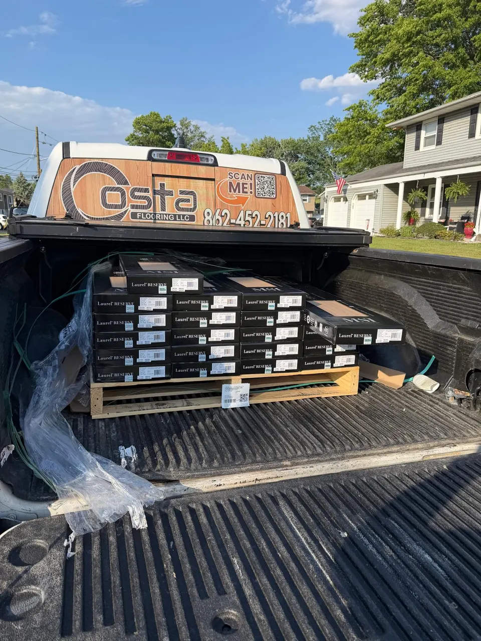 Costa Flooring truck loaded with boxes of hardwood flooring on a job site