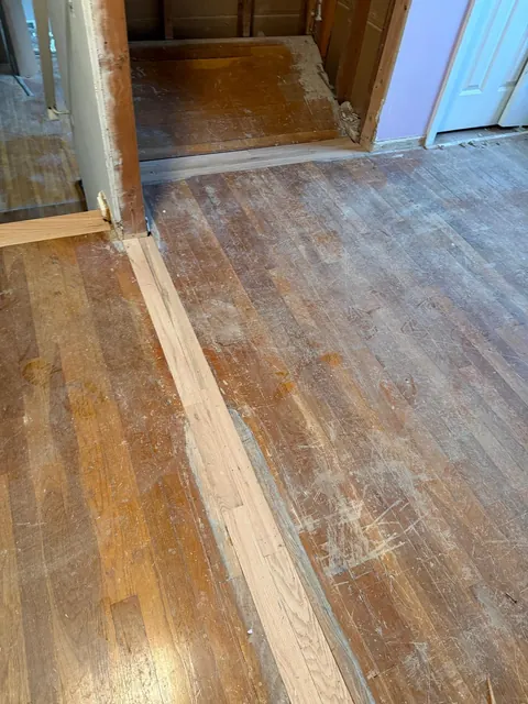 Before: worn hardwood floor with patched boards and a dull gray finish