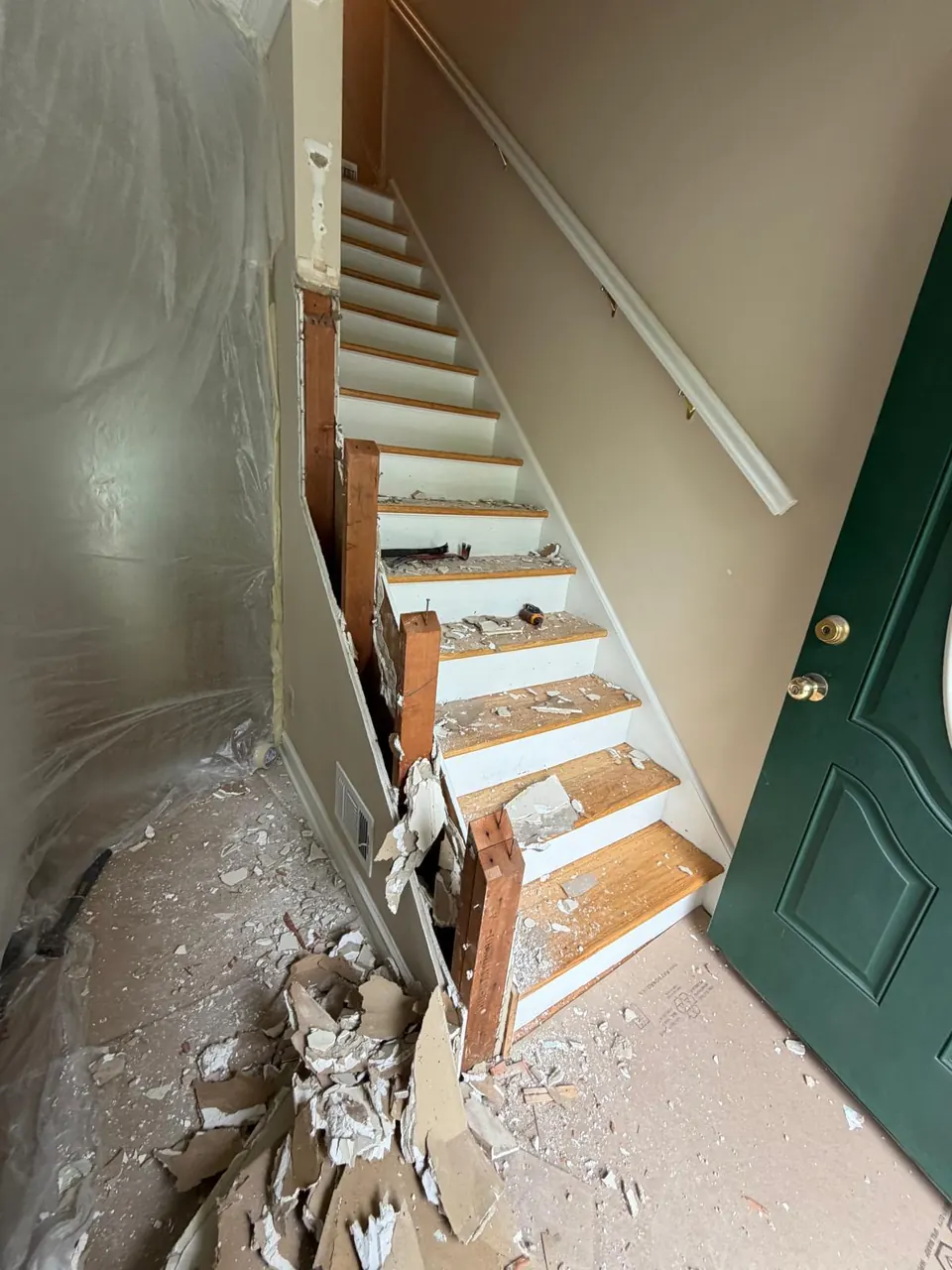 Before: staircase with damaged treads and debris beside a green front door
