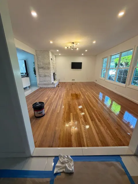 Open living room with refinished oak floor and stone fireplace