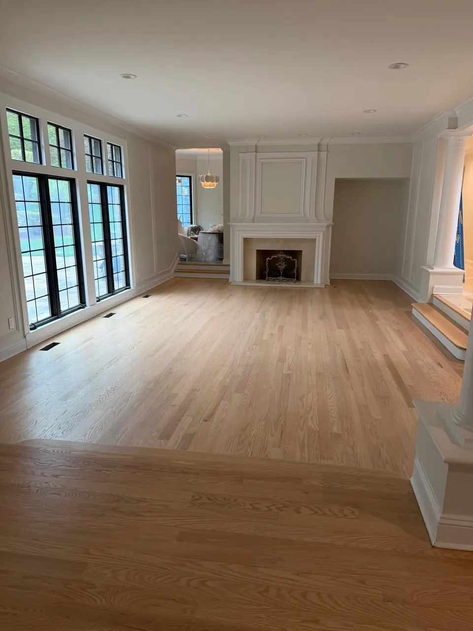 Open living room with a fireplace and a newly refinished light oak floor